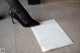 A woman in black high heels standing next to a piece of paper.