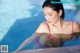 A woman in a pink bikini sitting in a pool.