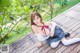 A woman in a school uniform is posing on a wooden deck.