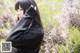 A woman in a black sweater standing in a field of flowers.