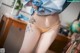 A woman in a blue shirt and yellow thong with a tattoo on her back.
