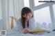 A woman laying on a bed reading a book.