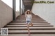 A woman in shorts and a hat is walking up some stairs.