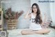 A woman sitting on the floor wearing glasses and a tank top.