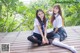 Two young women in school uniforms sitting on a wooden deck.